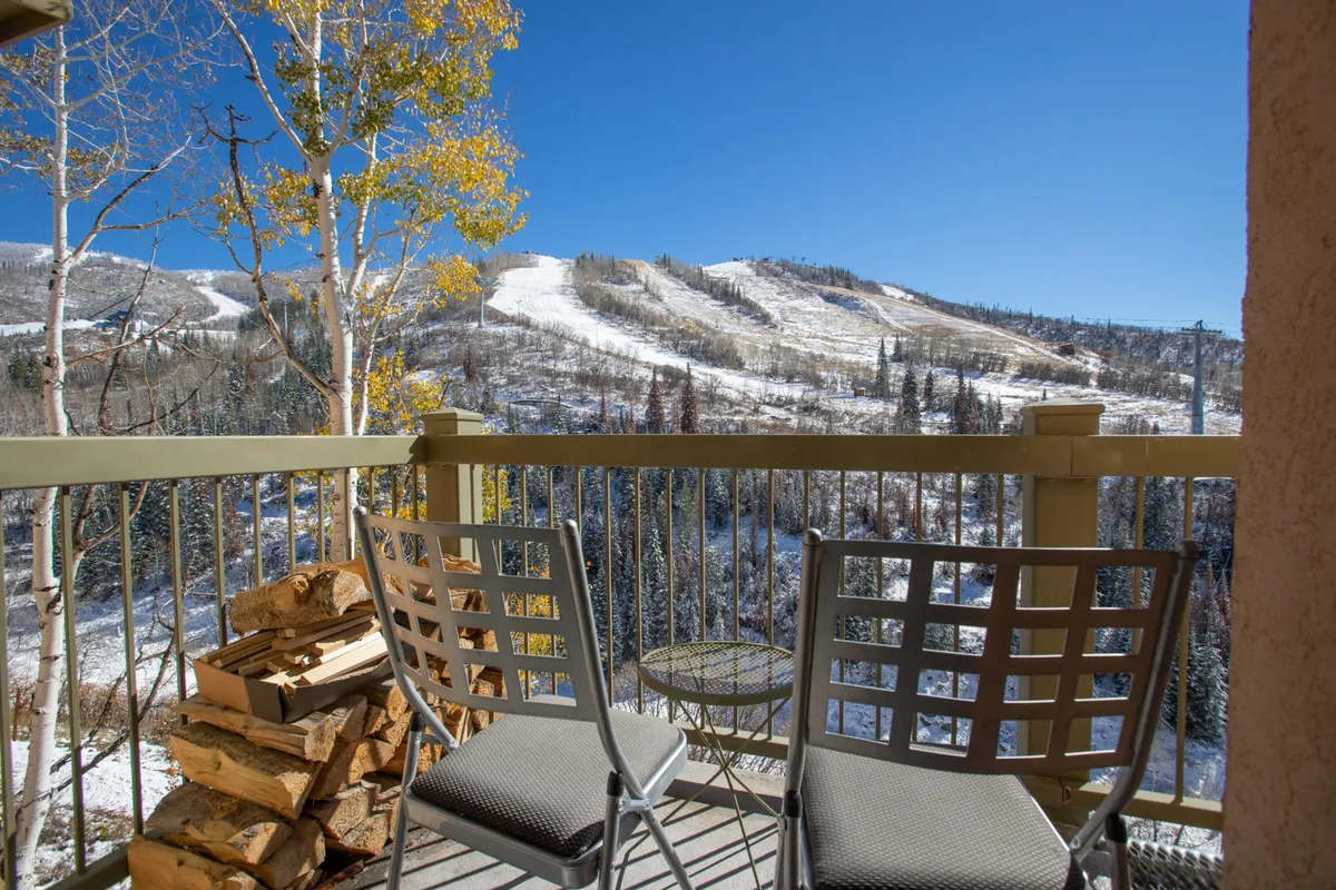 An exterior balcony scene with comfortable seating and a panoramic view of the mountains, perfect for relaxing or socializing after a day on the slopes. The scene captures the tranquil, sun-kissed ambiance described for après-ski moments and offers a direct connection to the stunning natural surroundings.