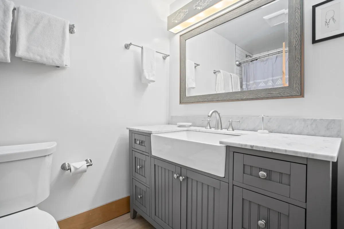 A modern, calm bathroom featuring a clean sink, expansive mirror, and bright vanity area. The setting is designed for personal grooming and relaxation, with soothing colors and ample lighting.