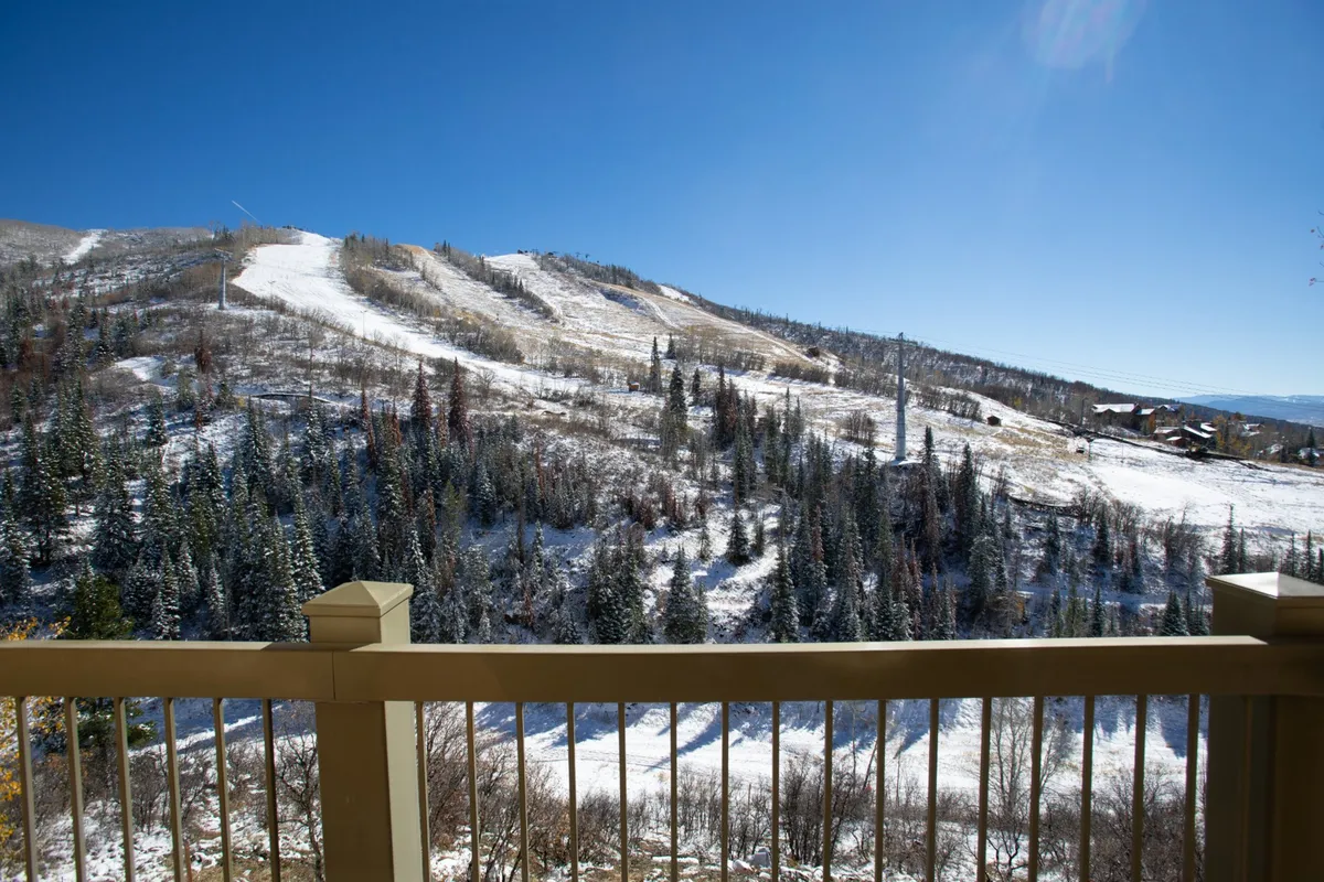 A breathtaking view of snow-covered mountains and dense evergreen trees beneath a clear blue sky. The scene encapsulates the serenity and grandeur of Steamboat’s landscape, ideal for inspiring productivity and relaxation alike.