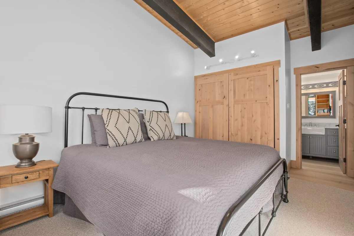 A tranquil secondary bedroom featuring twin beds with soft gray bedding, decorative pillows, and a wooden nightstand with a lamp. The room exudes a calming, welcoming vibe, perfect for children, friends, or multi-generational guests.